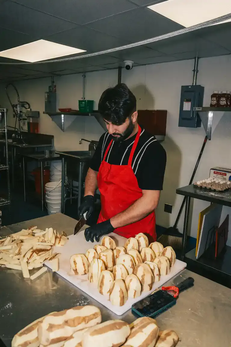 Chef hand-cutting fresh whole potatoes into Dutch-style fries in the kitchen at FRIES B4 GUYS, 485 Cambridge Street, Allston, Boston