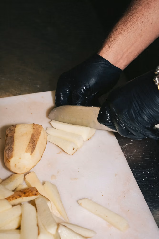 Chef hand-cutting fresh potatoes into Dutch-style fries