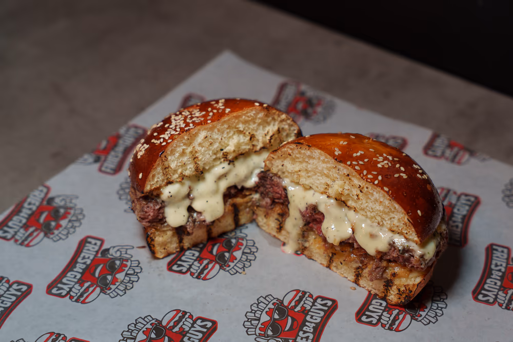 The Blue Royal, a contender for the best halal burger in Boston, cut in half to show blue cheese sauce over the patty on a sesame bun