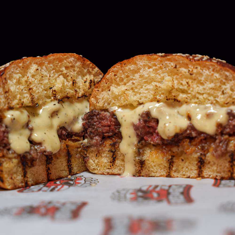 The Blue Royal cut in half, blue cheese sauce over the patty on a sesame bun