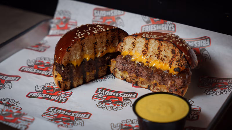 Halal burger cut in half with melted American cheese on a sesame bun