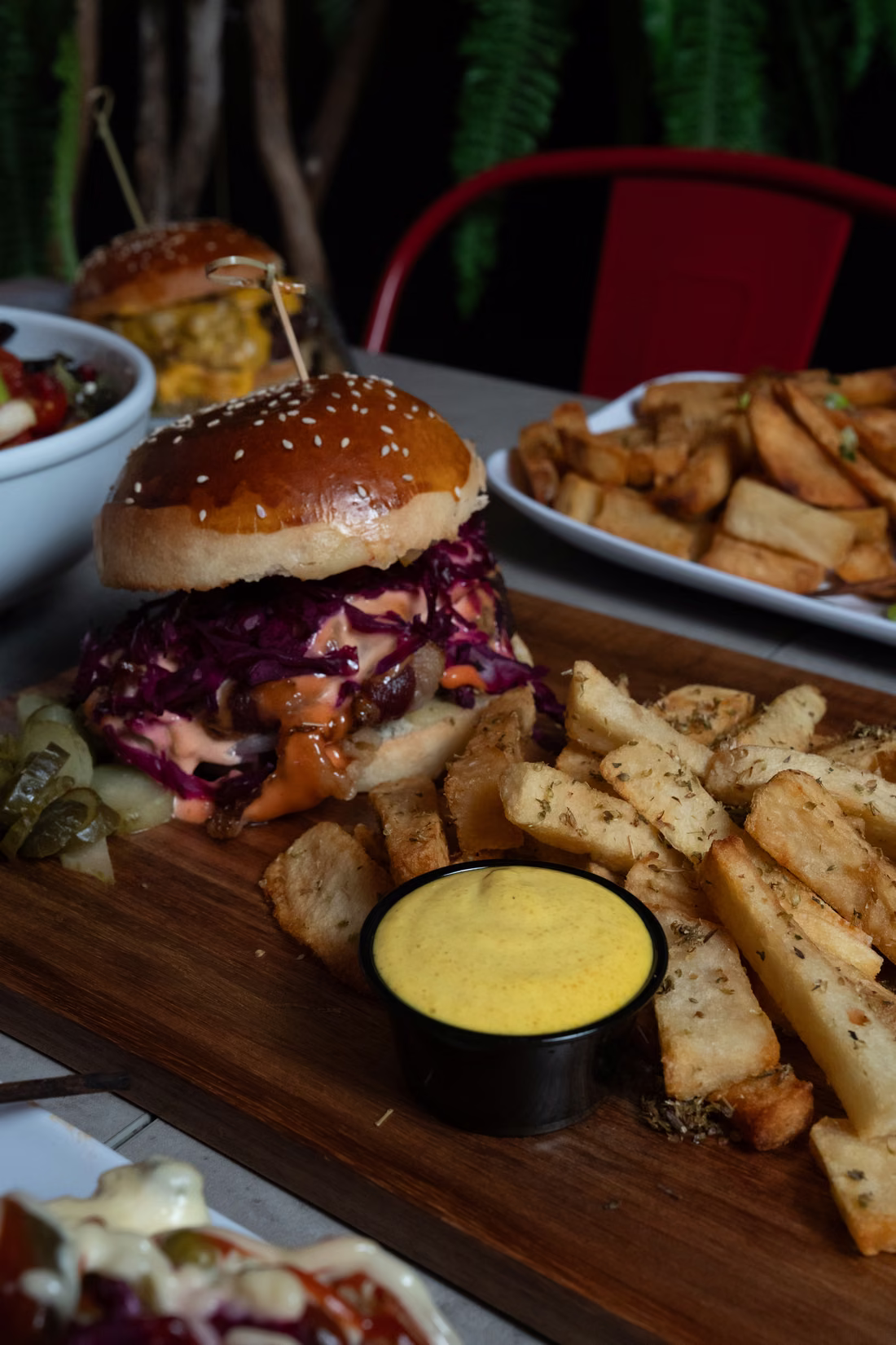 A burger with purple cabbage and house sauce next to hand-cut Dutch-style fries on the table at FRIES B4 GUYS in Allston, Boston