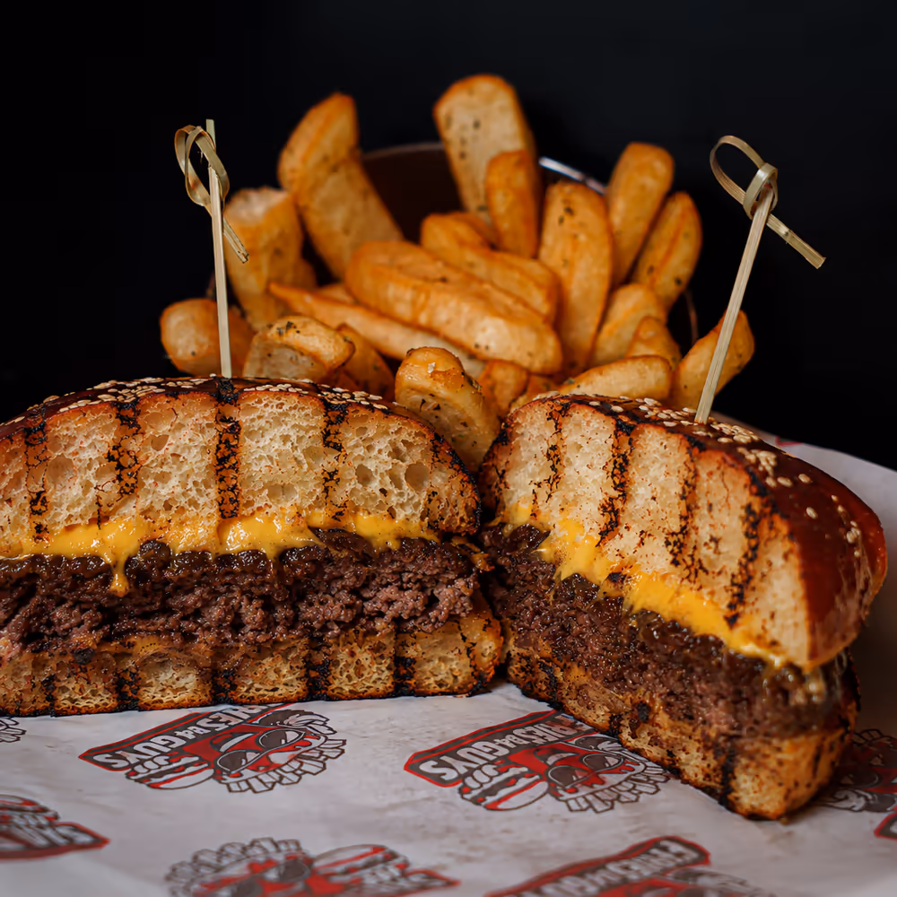 The FBG Burger cut in half with a basket of Dutch-style fries behind it