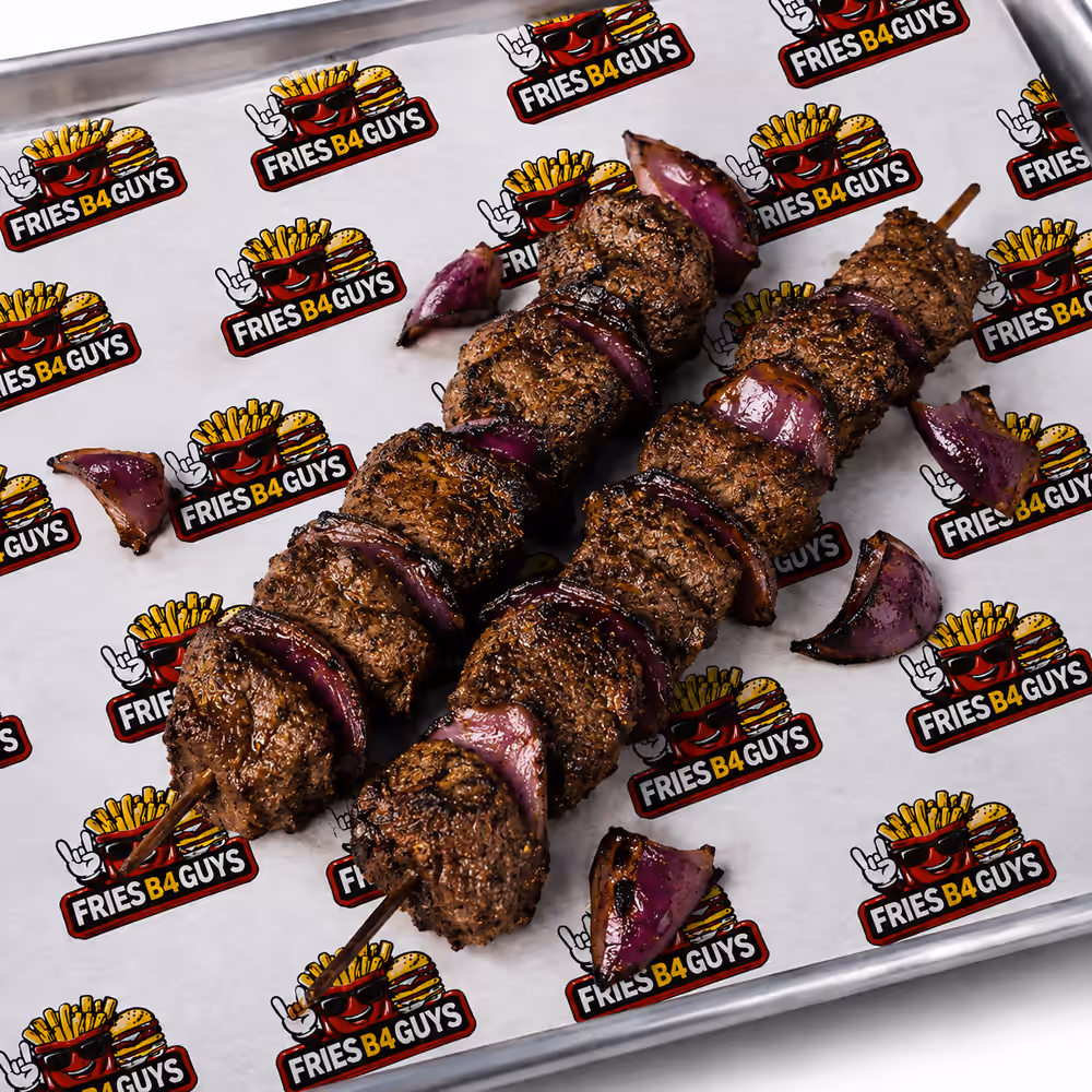 Halal picanha skewers with charred red onion on FRIES B4 GUYS paper on a metal tray