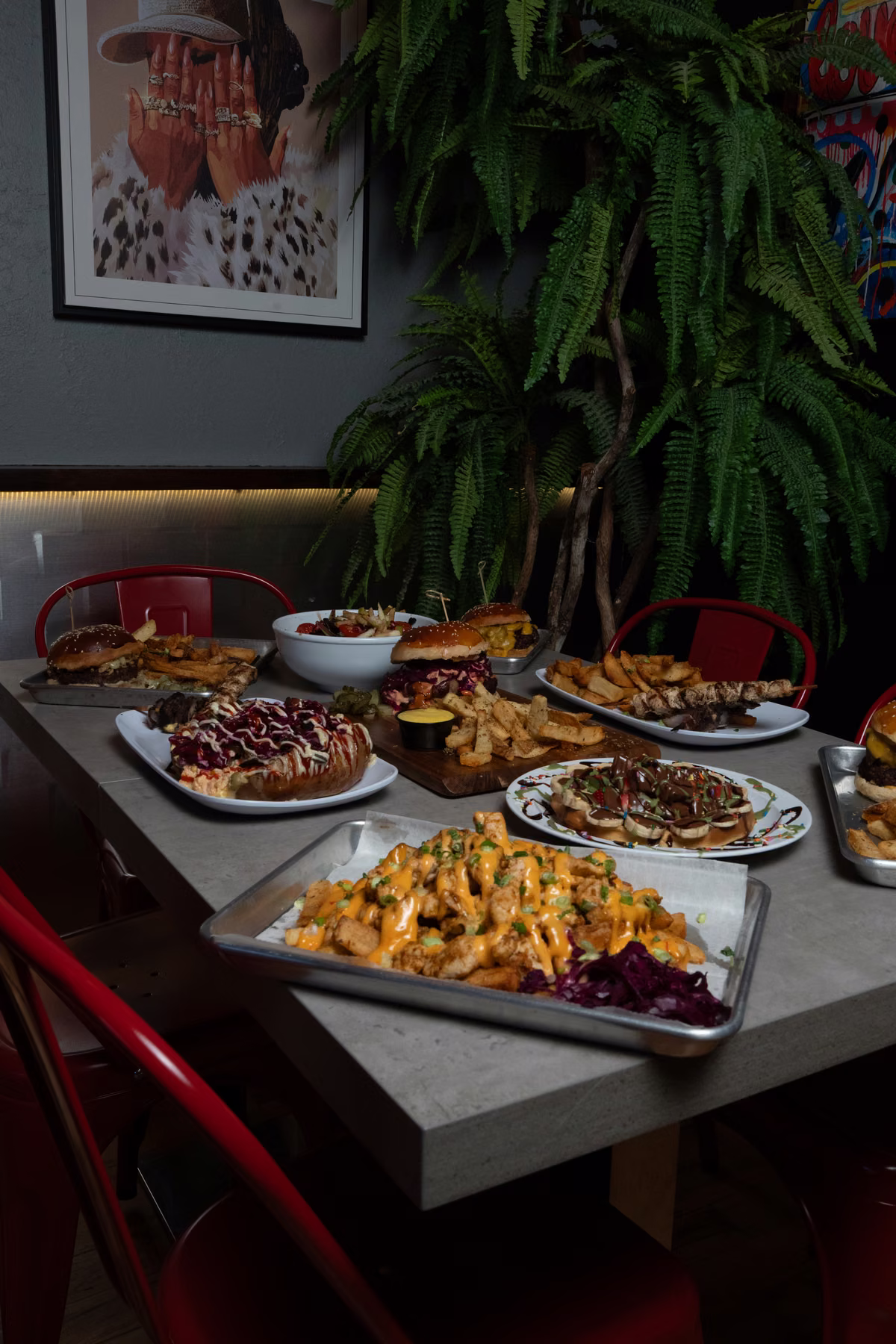 A full table of burgers, hand-cut Dutch-style fries and loaded fries in the dining room at FRIES B4 GUYS, Allston, Boston